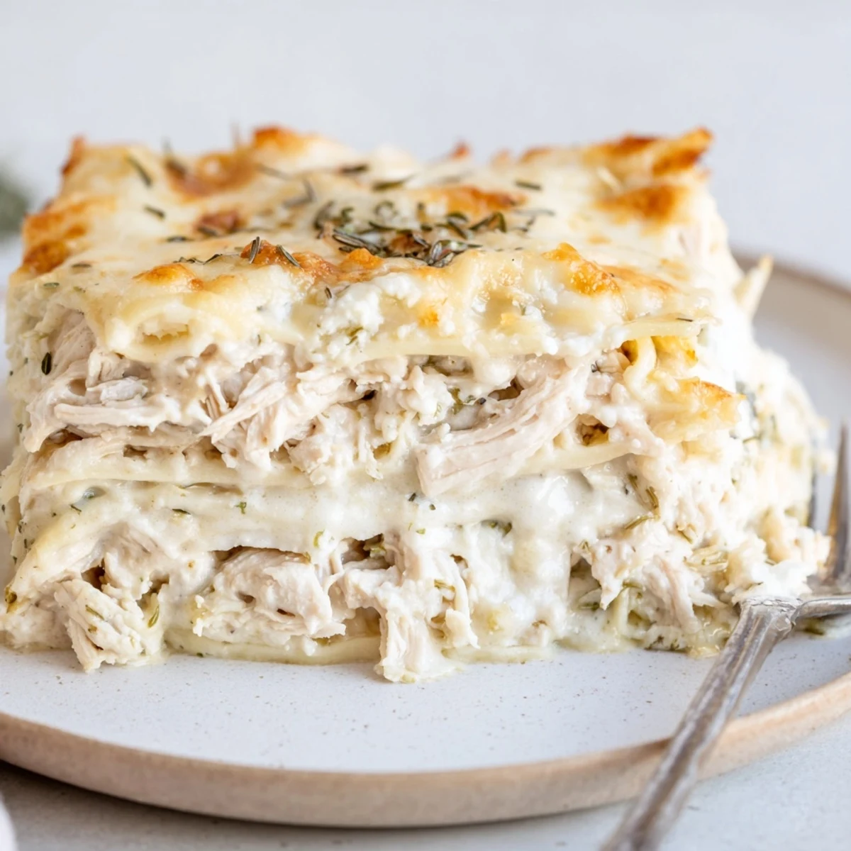 Savory rosemary chicken lasagna baked until golden, bubbling with creamy cheese layers.  