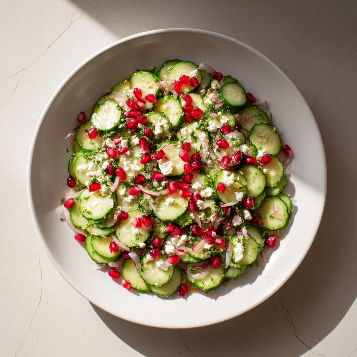 Close-up of a refreshing Healthy Cucumber Christmas Salad: crunchy cucumbers, reds, and bright pomegranate seeds.