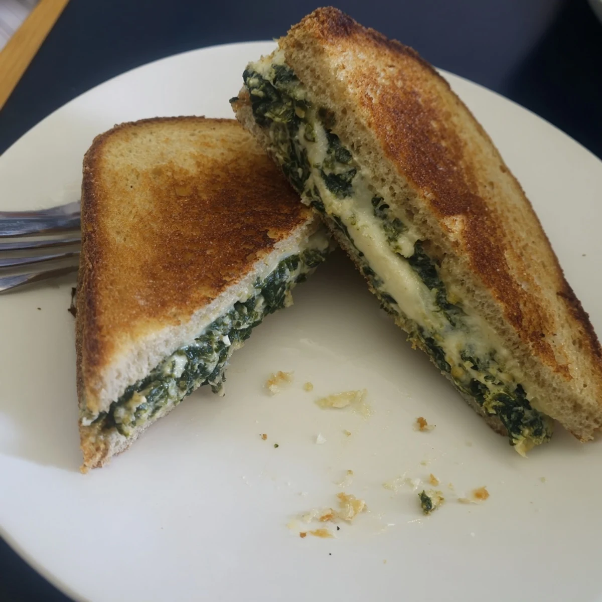 Golden-brown Sourdough Spinach Artichoke Dip Grilled Cheese, oozing with melted cheese and creamy dip.