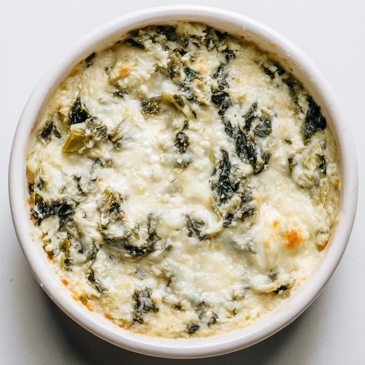 A close-up of cheesy, flavorful Spinach Artichoke Dip, seasoned and baked for a perfect appetizer.