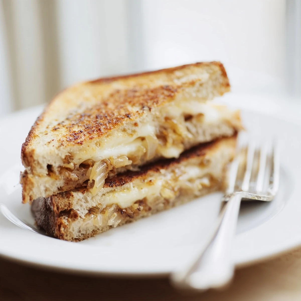 A close-up view shows the Crispy Onion Grilled Cheese cut diagonally, revealing layers of melted cheese and crunchy onion filling.