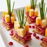 A detailed close-up of the Layered Urban Skyline, showcasing flavorful cheese cubes and folded meats atop crackers.