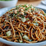 Vibrant sesame noodles recipe topped with fresh cucumber, scallions, and sesame seeds.