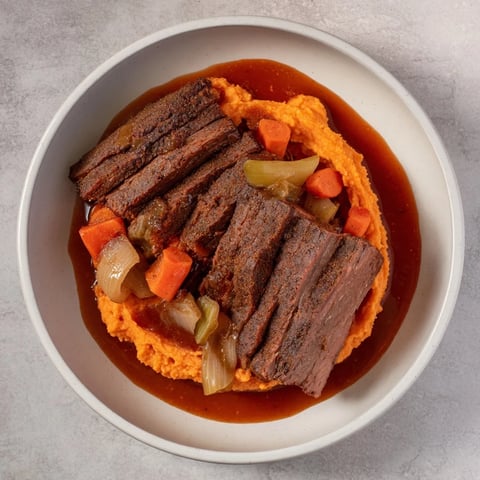 Hearty plate of classic brisket with tender sweet potatoes, an American comfort food dinner.
