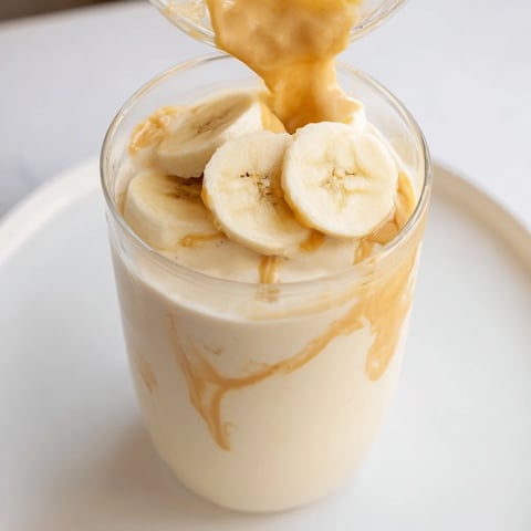 A tall glass filled with a creamy Peanut Butter Banana Smoothie, ready for a refreshing sip.