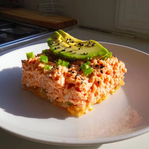 Golden, crispy Spicy Tuna Crispy Rice squares topped with vibrant red and green garnishes ready to eat.