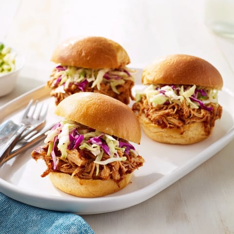 Soft mini slider buns stuffed with saucy pulled BBQ chicken and cool, crunchy slaw for game day.  