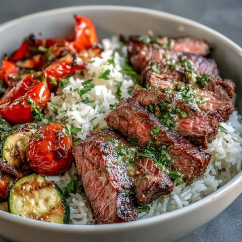 Steaming bowl of Grilled Steak Bowl with fluffy rice and vibrant chimichurri sauce.