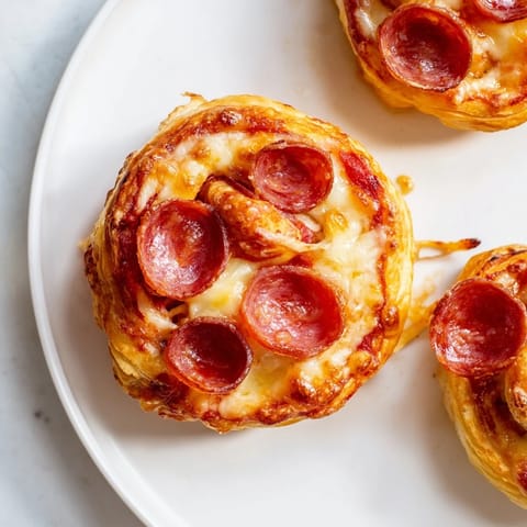 Close-up of baked Mini Pepperoni Pizza Pinwheels showcasing melted cheese and savory pepperoni.
