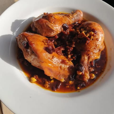 A beautiful photo of Budget Fesenjan, with a glistening, dark, savory sauce surrounding chicken.