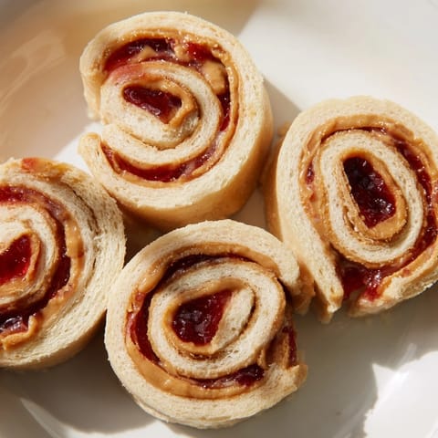 Quartered PB&J pinwheel rolls, showing vibrant swirls of peanut butter and jelly, ready to eat.