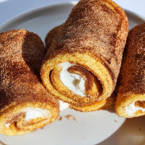Close-up of fluffy Easy French Toast Roll-Ups, showcasing the sweet cinnamon sugar crust on a plate.