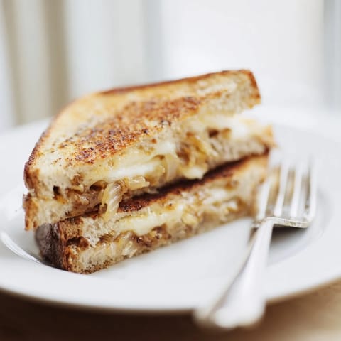 A close-up view shows the Crispy Onion Grilled Cheese cut diagonally, revealing layers of melted cheese and crunchy onion filling.