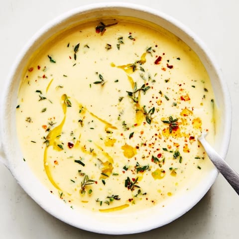 A close-up of creamy Cowboy Butter Sauce in a bowl, garnished with lemon zest and red pepper flakes for a bold kick.