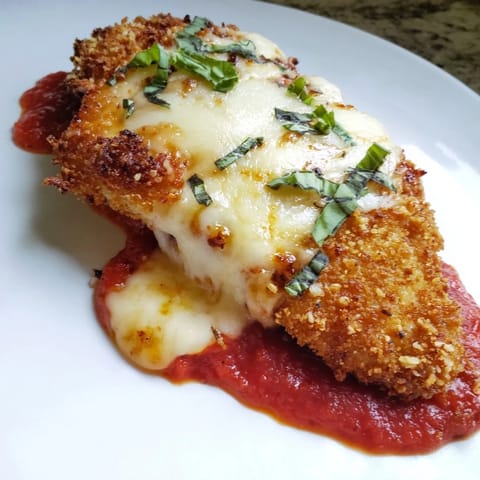 Crispy Chicken Parm Wrap cut in half, revealing layers of rich sauce, gooey cheese, and fresh basil.