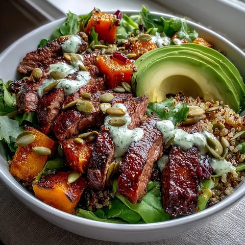 A close-up view of a vibrant butternut squash steak bowl with greens and lime dressing.