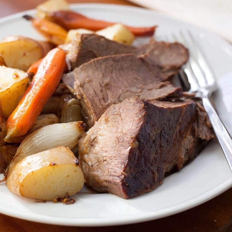 A close-up of a flavorful Sunday Pot Roast, with braised beef and root vegetables.