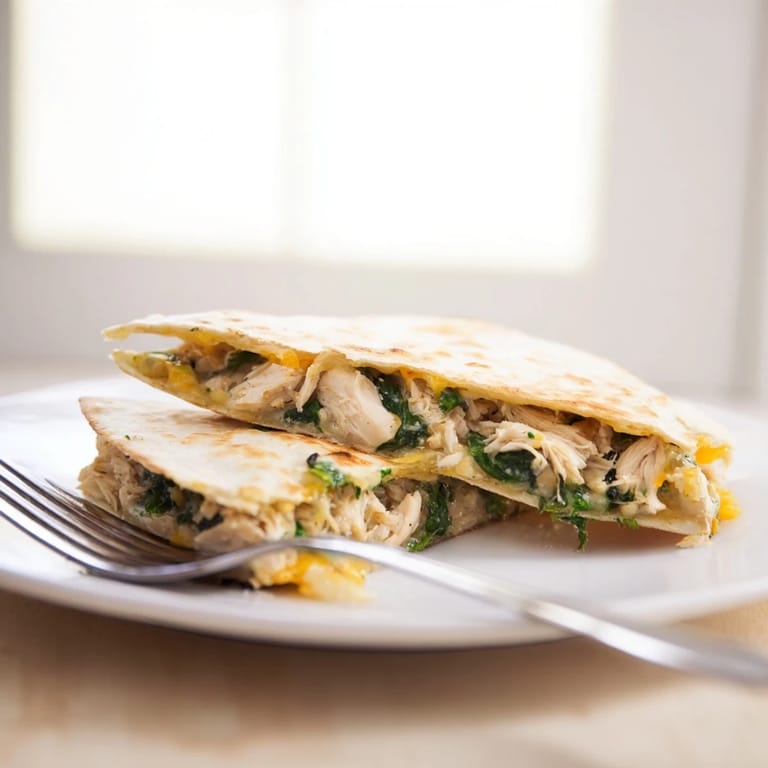 Freshly grilled Chicken and Spinach Quesadilla served on a plate, ready to be enjoyed with a side of cool sour cream.