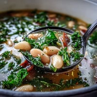 Hearty Kale and White Bean Soup with Lemon and Garlic in a rustic white bowl, garnished with fresh parsley.